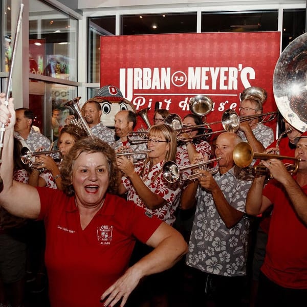A lively band plays brass instruments inside Urban Meyer's Pint House, with a woman leading.