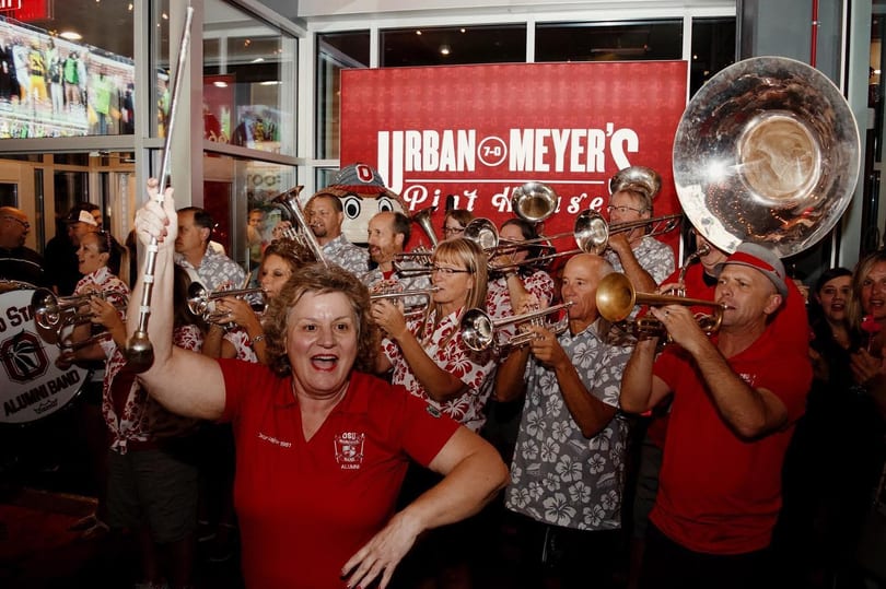 A lively band plays brass instruments inside Urban Meyer's Pint House, with a woman leading.