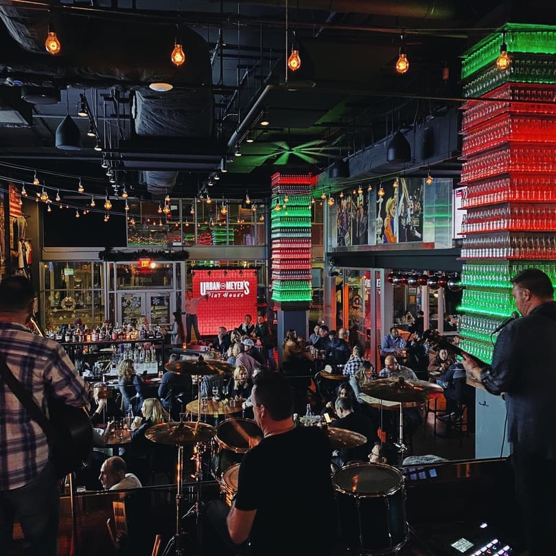 A lively bar with a band performing on stage and patrons seated at tables enjoying the music.