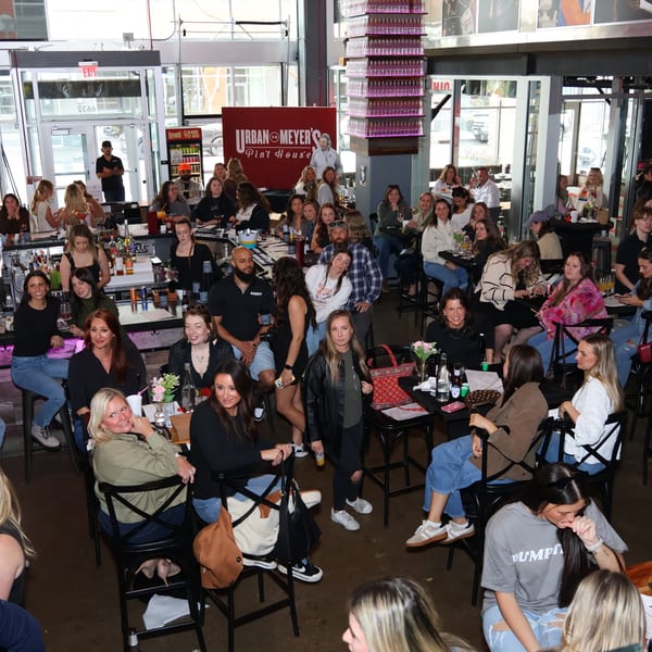 A large group of people, mostly women, socializing in a lively bar or restaurant.