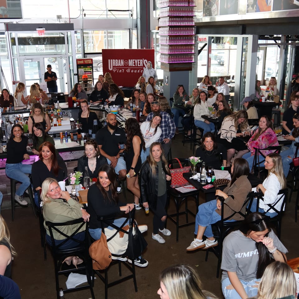 A large group of people, mostly women, socializing in a lively bar or restaurant.