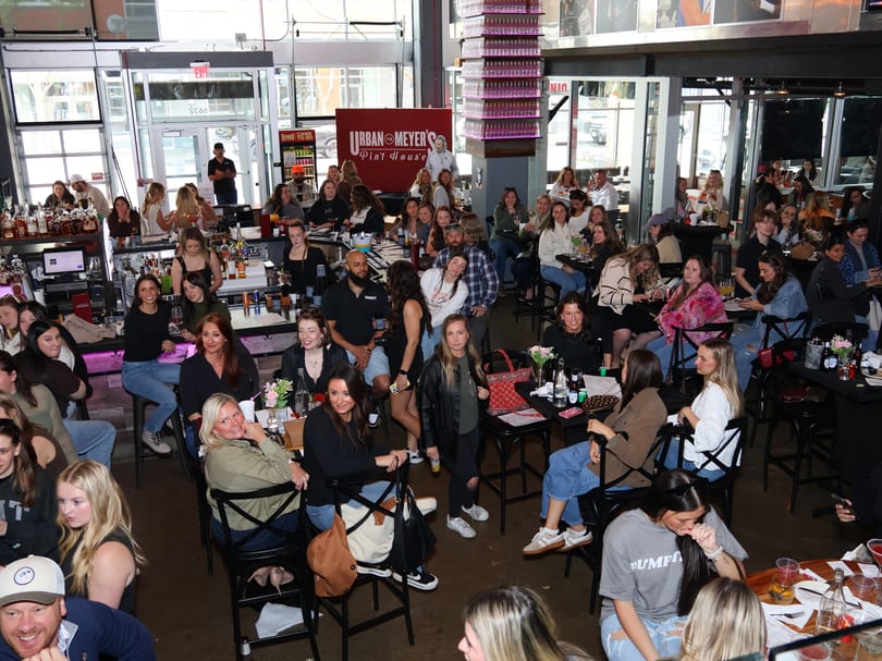 A large group of people gathered at tables and a bar inside Urban Meyer's Pint House.