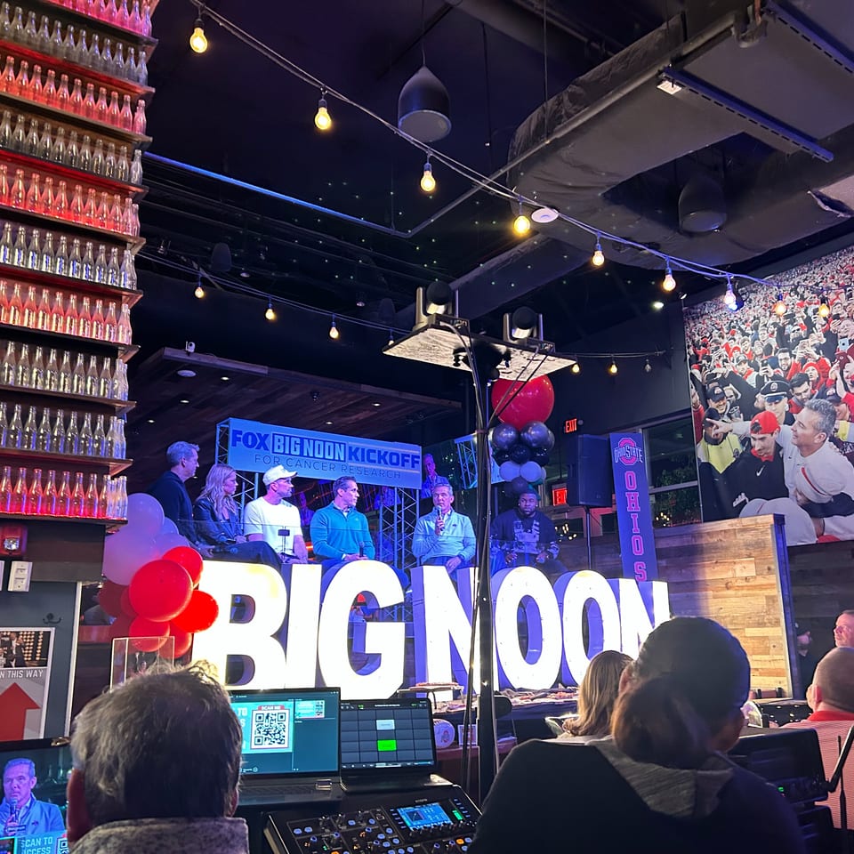 A panel of five men sit on a stage with "BIG NOON" in large letters, for a Fox Big Noon Kickoff event.