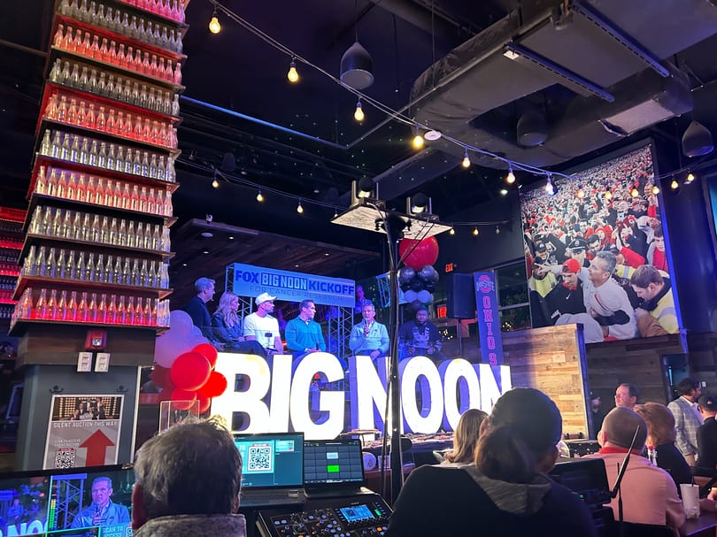 A panel of five men sit on a stage with "BIG NOON" in large letters, for a Fox Big Noon Kickoff event.